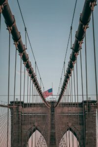 Top of famous s4th of july photo, uspension Brooklyn Bridge with American flag under cloudless blue sky